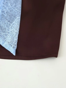 Detail of blue floral lace stitching and dark brown fabric on the high-waist skirt set