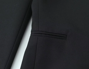 Gros plan d'un tailleur noir montrant une poche passepoilée précise et la texture du tissu