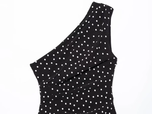 Detailed view of one-shoulder neckline and pleated polka dot fabric on the dress