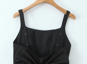 Détail d'une robe noire dos nu montrant bretelles réglables, zip et plis délicats