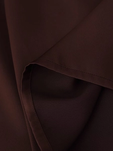 Detailed view of chocolate brown fabric with silky sheen and neat stitching on skirt
