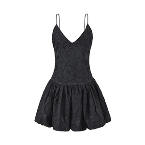 Détail de robe noire à col en V avec tissu jacquard texturé et ourlet bulle bouffant