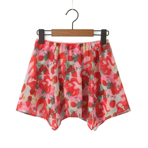 Close-up of red floral chiffon skirt with strawberry and flamingo print on wooden hanger