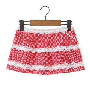 Detail of red polka dot midi skirt with lace trim and pink floral bows on a white hanger