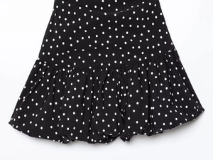 Detailed view of black polka dot mini skirt featuring pleated hem and puff texture