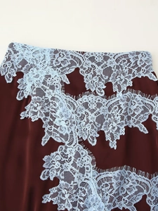 Macro detail of burgundy satin fabric with light blue floral lace and eyelash trim
