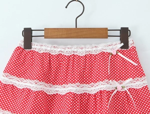 Detail of red polka dot skirt featuring white lace tiers and silk ribbon bows