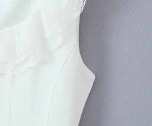 Close-up of white summer dress featuring elegant lace trim and ruffle edge details