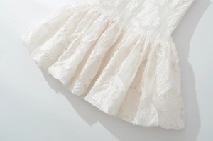 Détail de robe blanche avec jacquard floral 3D et texture de l'ourlet à volants