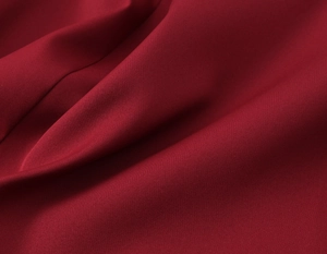 Close-up of deep red fabric texture showing fine weave and soft drapery on a suit jacket