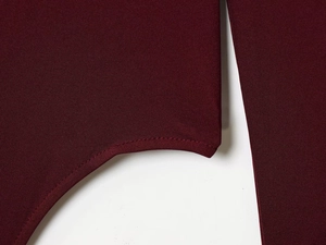 Detail of burgundy ribbed knit fabric showing square neckline seam and stitching quality