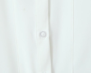 Detailed macro view of delicate white lace fabric with button and refined stitching detail