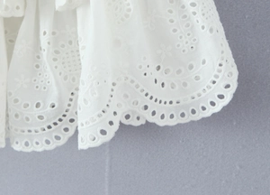 Detail of white cotton eyelet embroidery with elegant scalloped edges and floral patterns
