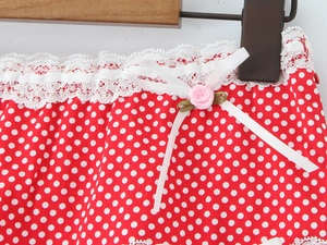 Detail of red polka dot fabric with white lace trim and pink rose ribbon bow decoration