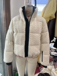Detailed view of white cable knit textured puffer jacket with high collar and black zipper