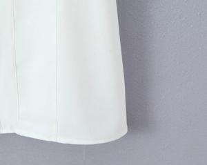 Detailed close-up of white summer dress hemline showing precision stitching and fabric