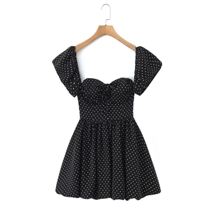 Detail of black polka dot mini dress featuring puff sleeves and tie-up neckline detail