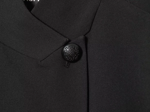 Close-up of black woven blazer lapel featuring an embossed crown crest button detail