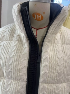 Detail view of cable knit texture and contrasting black zipper on white winter jacket