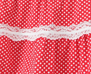 Macro shot of red polka dot fabric with delicate white double-layer lace trim detail