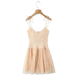 Close-up of champagne lace dress featuring adjustable ribbon straps and floral embroidery