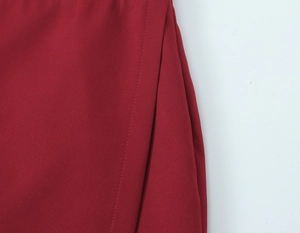 Macro shot of side stitching detail on deep red woven fabric of the fashion suit set
