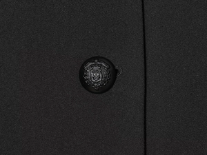Macro detail of ornate heraldic button on high-quality black blazer fabric texture
