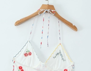 Detail of white halter neck top featuring delicate cherry and floral embroidery accents