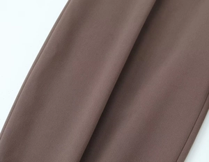 Detail of the taupe woven fabric showing high-quality side stitching on fashion trousers