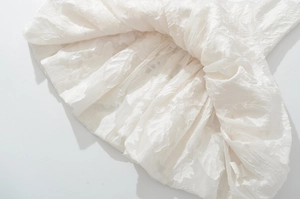Vue détaillée du tissu blanc d'une robe à volants avec broderie florale 3D et plis