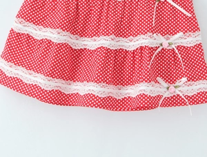 Detail of red polka dot skirt hem with three-tier lace and rose ribbon bow accent