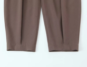 Detailed macro view of brown textured trousers showing crisp creases and fine fabric weave