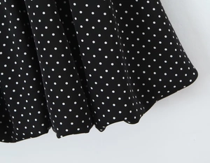 Detail of black dress fabric with white polka dot pattern and elegant ruffled hem