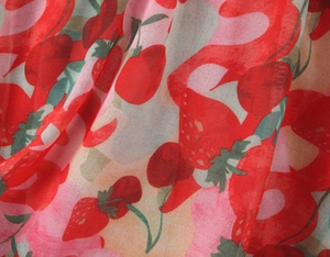 Detail of red strawberry and cherry print on lightweight pink chiffon fabric