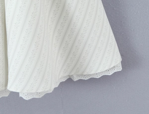 Détail d'une robe d'été fleurie avec bordure en broderie anglaise et rayures fines