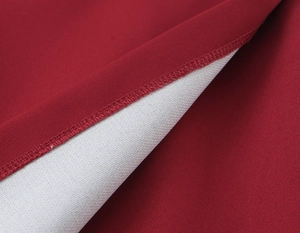 Close-up of precision double stitching and deep red fabric texture on a woman blazer