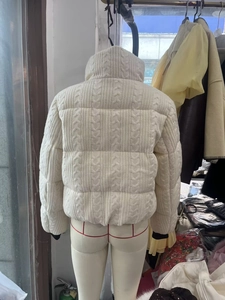 Detailed back view of a beige cable-knit padded jacket with stand collar and rib cuffs