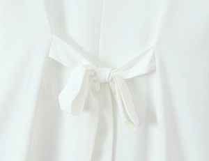 Close-up of the delicate white tie-back bow detail on a summer lace dress waistline
