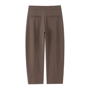 Detail of high-waisted brown trousers with crisp vertical creases and back welt pockets