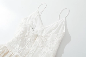 Détail de dentelle blanche sur une robe à col en V avec lacets au dos et fermeture éclair