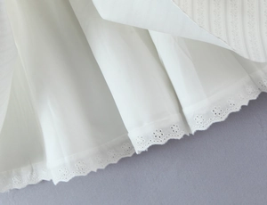 Détail de l'ourlet en broderie anglaise blanche et du tissu texturé multicouche doublé