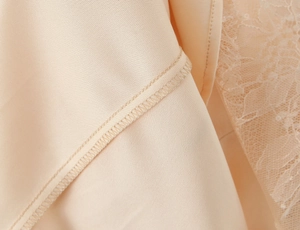 Detailed close-up of beige dress seams with delicate lace trim and subtle sequin accents