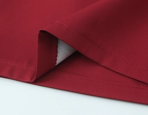 Close-up of deep red fabric texture with precise hem stitching and smooth finish