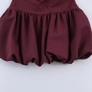 Detail shot of a burgundy summer dress showing the voluminous bubble hem and pleated fabric