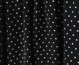 Close-up of lightweight black fabric with classic white polka dot pattern and soft draping
