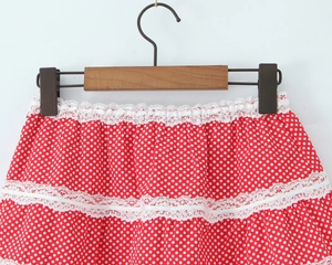 Detail of red and white polka dot skirt with decorative white lace trim and layered fabric
