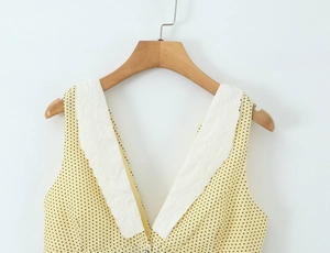 Close-up of V-neck sleeveless top with white floral lace trim and black polka dots