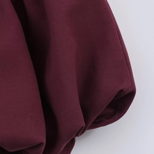 Close-up of deep wine red dress fabric showing elegant pleated texture and balloon sleeves