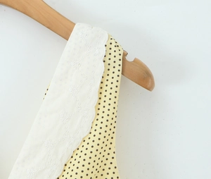 Close-up of yellow polka dot fabric with delicate white floral lace embroidery details