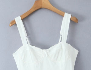 Detailed view of white cotton camisole with lace trim and small bow on the neckline
